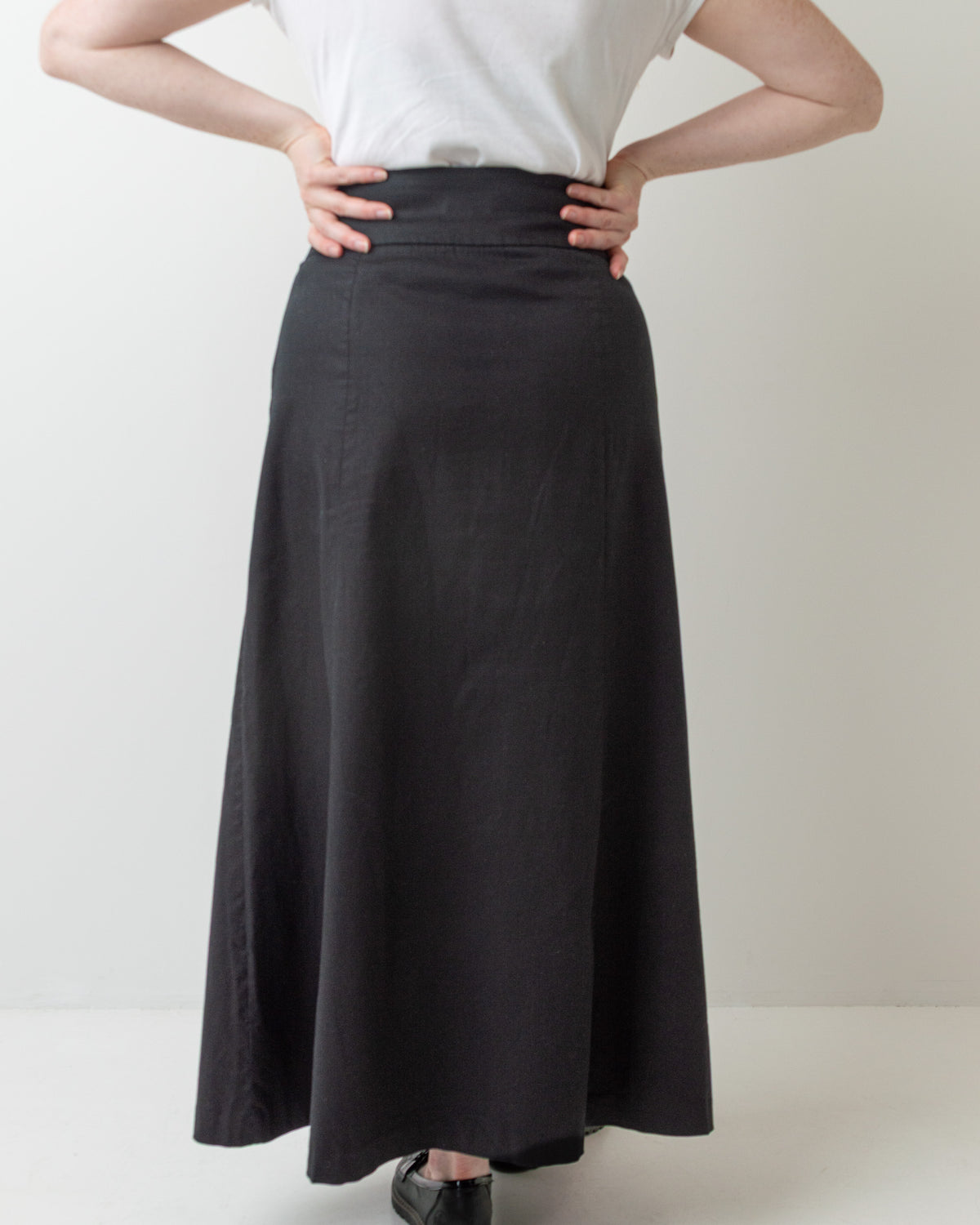Wittenfelt Black A-Line Maxi Skirt, back view with hands on hips